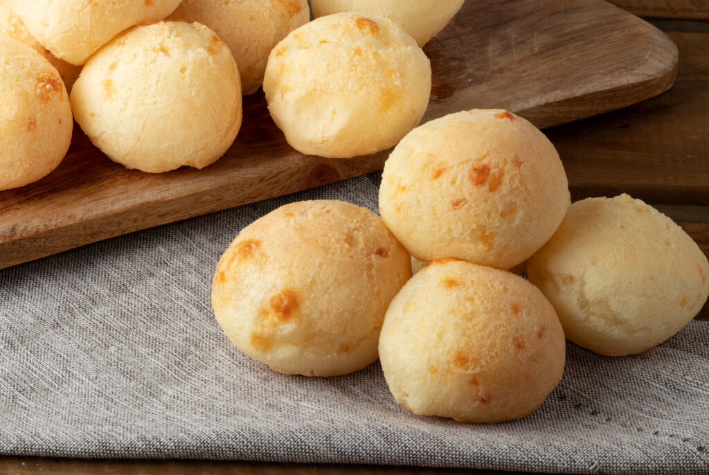 Freshly baked Brazilian cheese bread pão de queijo on a wooden cutting board